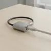 Câble réseau gris clair branché dans la prise RJ45 de l'adaptateur, posé sur une table en bois clair