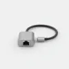 Adaptateur USB-C vers RJ45 en aluminium gris posé sur fond clair, prise réseau de face et câble court terminé par une fiche USB-C