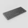 Clavier compact sans fil gris graphite vu de trois quarts sur fond gris clair, tranche fine visible