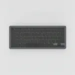 Clavier compact sans fil gris graphite à touches noires sans inscription, vu de dessus sur fond gris clair