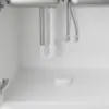 Détecteur posé au fond d'un meuble sous évier, sous le siphon et les flexibles d'arrivée d'eau