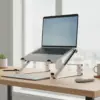 Ordinateur portable ouvert posé sur le support en aluminium, avec un clavier et une souris séparés sur le bureau