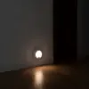 Veilleuse allumée au bas du mur d’un couloir, au-dessus de la plinthe, éclairant le parquet