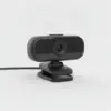 Webcam vue de trois quarts, avec sa charnière, sa pince et son câble USB, sur fond gris clair